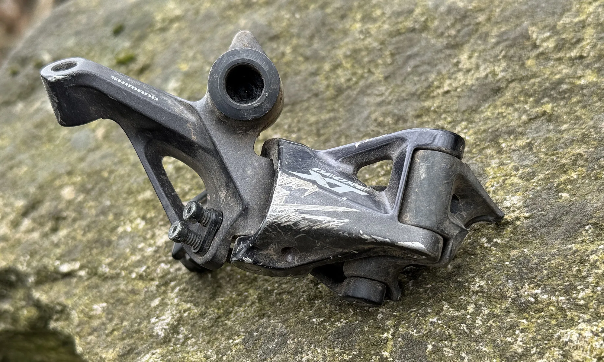 deragliatore di shimano xt rotto dove la gabbia appese su una roccia